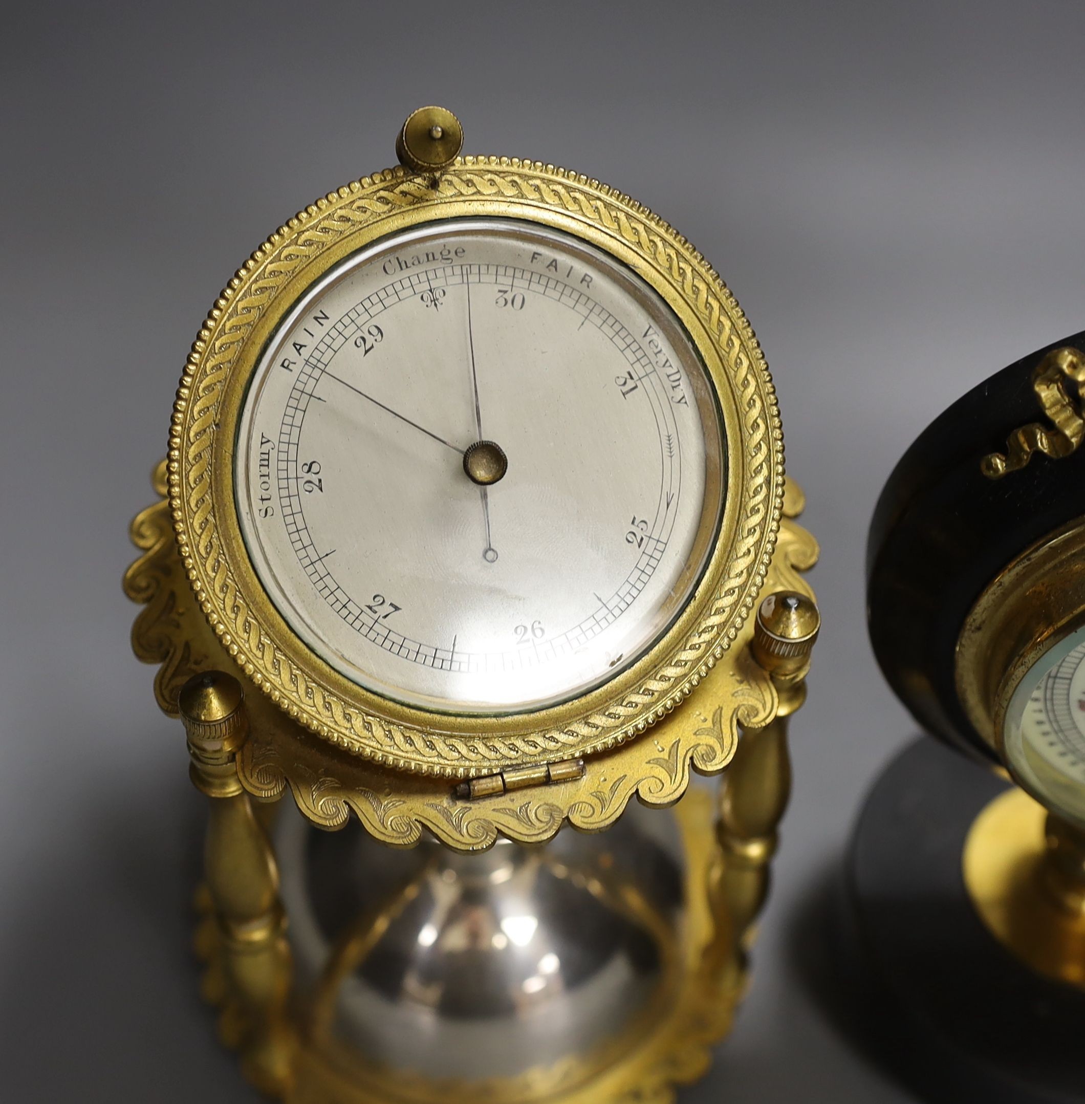 An ormolu and silver plated hourglass shaped desk aneroid barometer and a gilt metal and parcel ebonised desk barometer